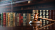 A gavel in front of a bookshelf full of legal texts.