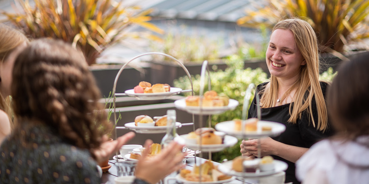 A group of people enjoying afternoon tea, and towers of cakes, on the Ashmolean rooftop