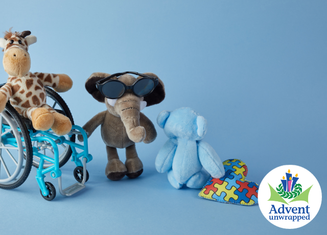 stuffed animals portrayed in a wheel chair, wearing glasses and holding a puzzle piece heart