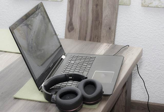 A laptop and headphones on a wooden desk.