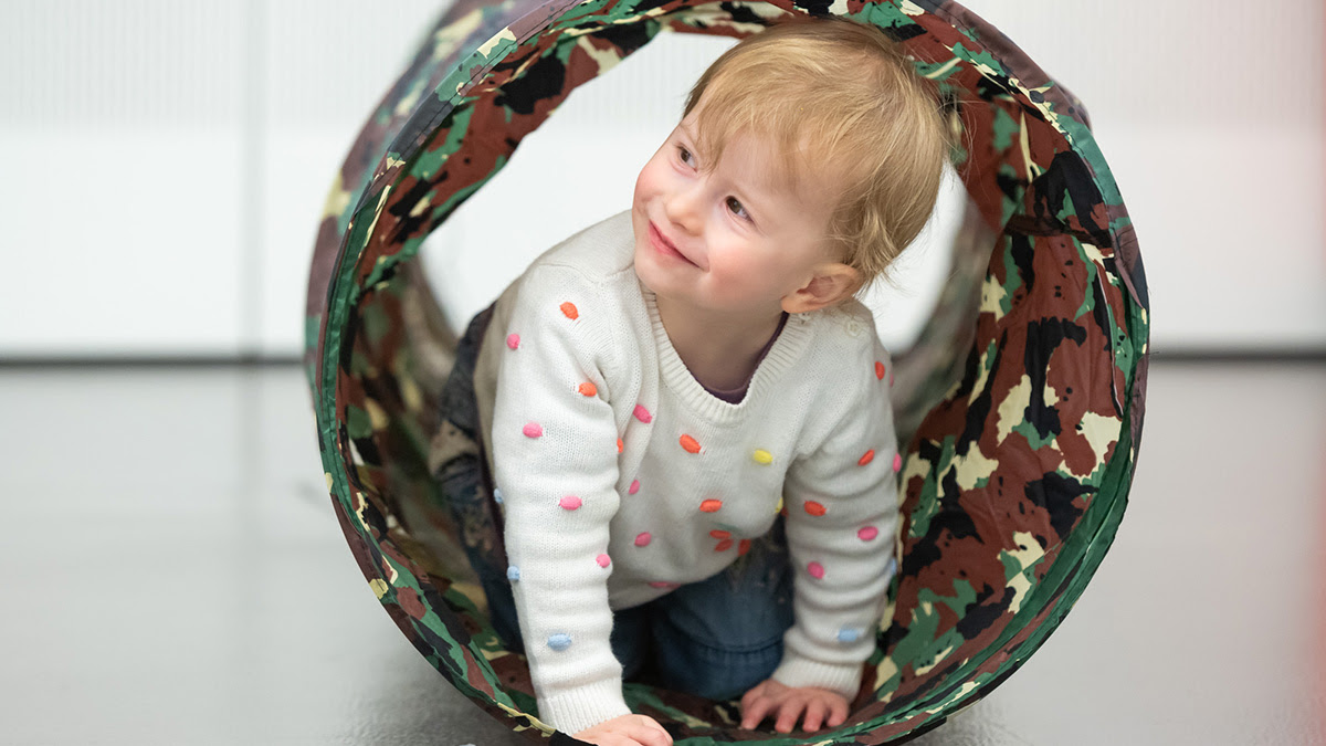 Toddler crawling through a play tunnel