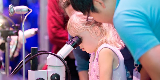 Ένα νεαρό κορίτσι κοιτάζει μέσα από ένα μικροσκόπιο