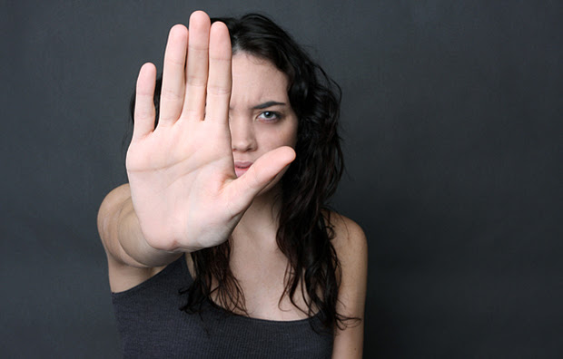 A teenage girl holding out her hand signalling to stop.