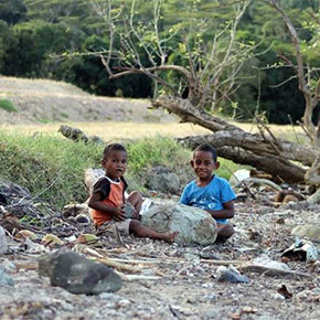 two young boys sitting in dried up creek bed