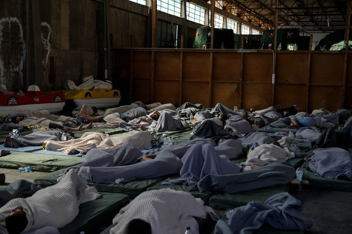 Survivors of the ship sleep in a warehouse in the port of Kalamata, Greece, where they were initially brought after their rescue. (Thanassis Stavrakis/AP)
