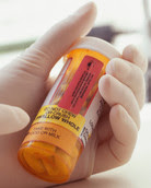 Gloved hand pointing at drug bottle label