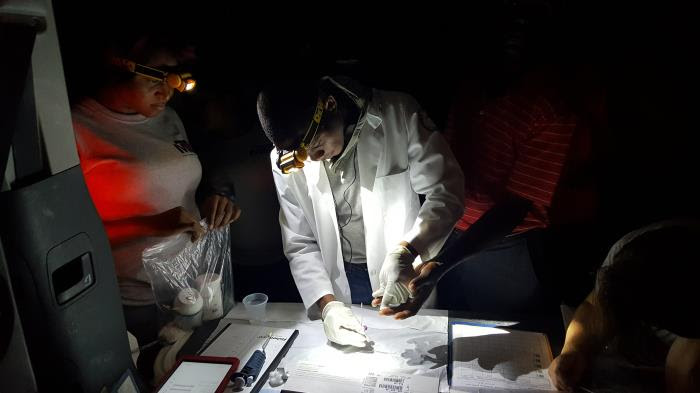 This photograph, depicts a lab tech, in the process of performing a fingerstick on a man in the community to extract a blood sample.