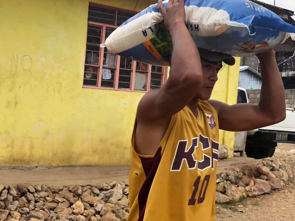 Photo of a man carrying a bag of rice on his head.