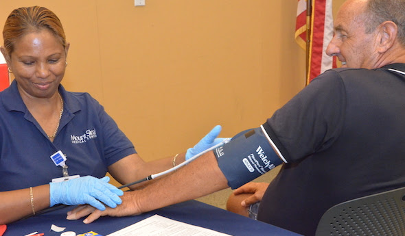 Mount Sinai Medical Center employee checking a man's blood pressure