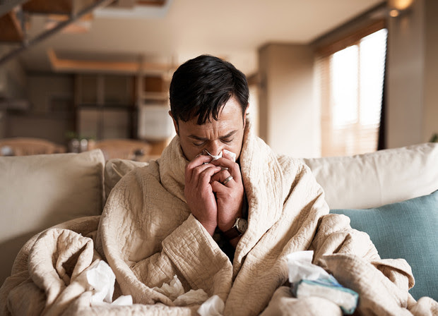 A sick man blowing his nose.