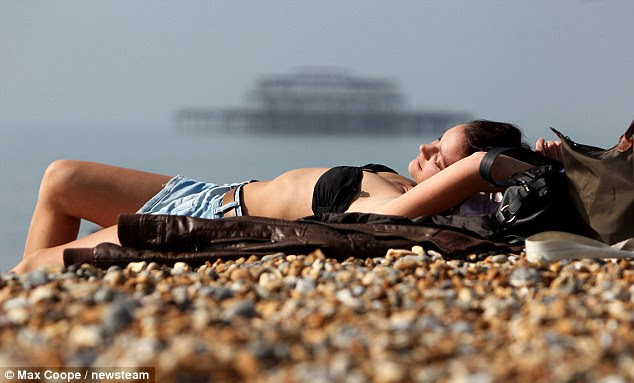Summer sun: A woman enjoying Brighton beach this morning