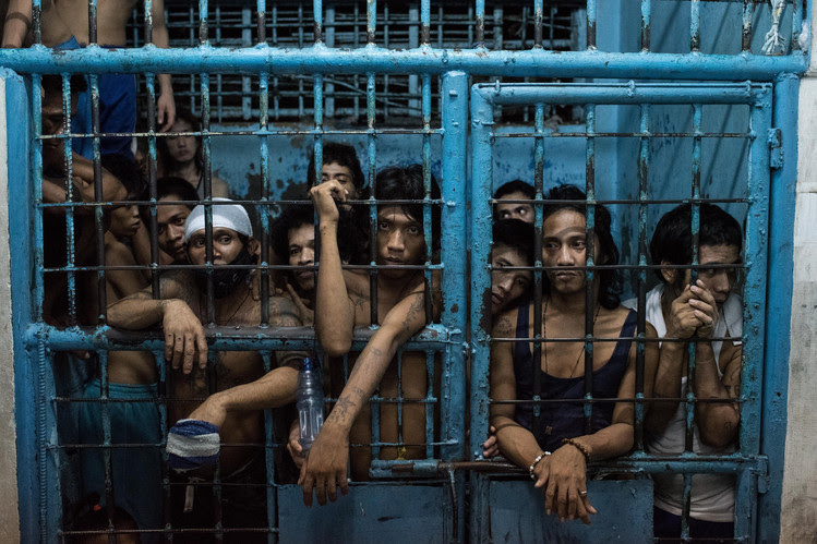 Inmates watched as drug suspects are processed inside a police station in Manila in October.