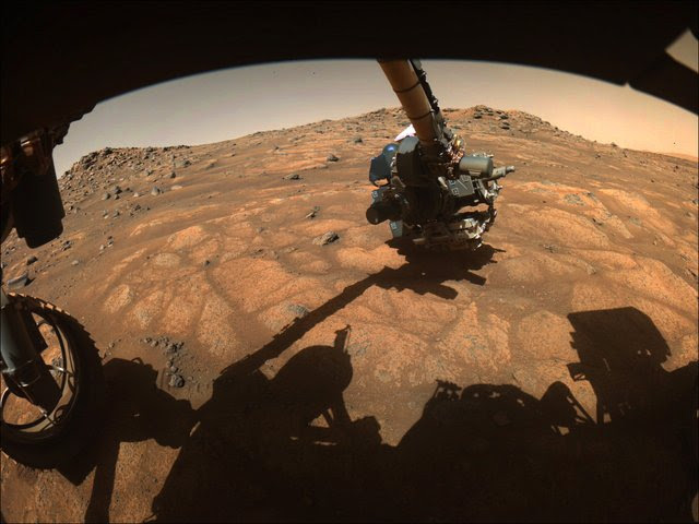 The robotic arm on NASA’s Perseverance rover reached out to examine rocks in an area on Mars nicknamed the “Cratered Floor Fractured Rough” area in this image captured on July 10, 2021 (the 138th sol, or Martian day, of its mission).