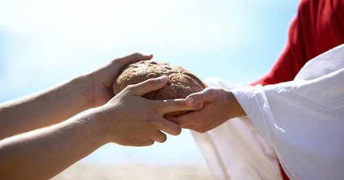 Hands passing a loaf of bread