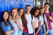 Teenage school kids smiling to camera in school corridor.