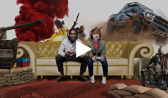 Video featuring two gamers playing on a couch with game scenes behind them.
