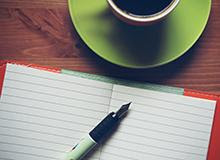 Cup of coffee and a pen and notebook on a table