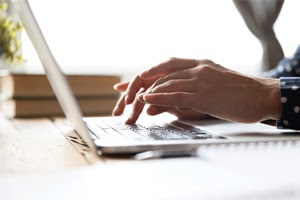 Hands typing on a laptop