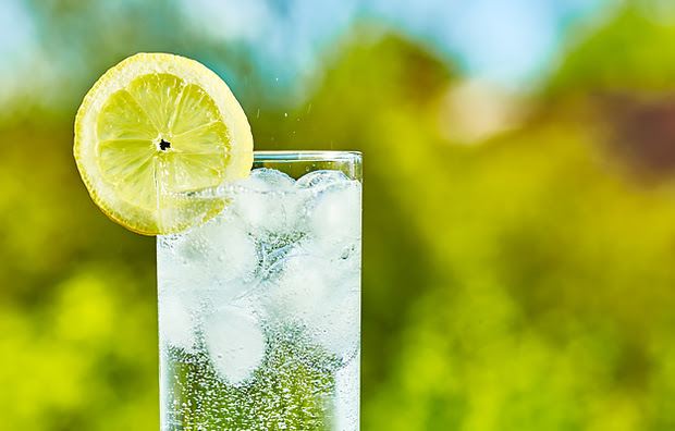 A glass of water with a slice of lemon.