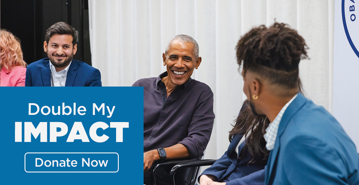 President Obama is seated in a chair and smiling at a young person with medium-dark skin and dark hair seated to his left. On the bottom right, words read "Double my impact, donate now"