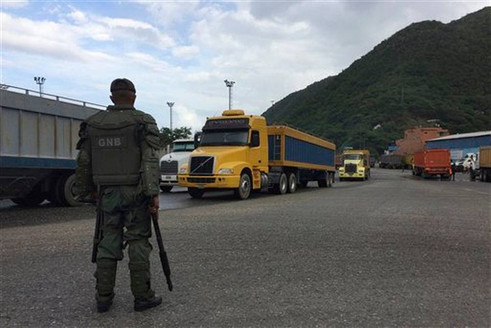 Un soldado de la Guardia Nacional vigila camiones que salen del puerto en Puerto Cabello, Venezuela, la ciudad portuaria por la que pasan la mayoría de importaciones de alimentos del país
(foto AP)