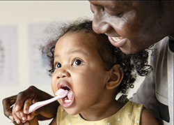 photo of a parent teaching their child how to brush their teeth