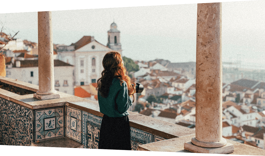 Image description: A lady admiring Lisbon’s coastline from a tiled balcony