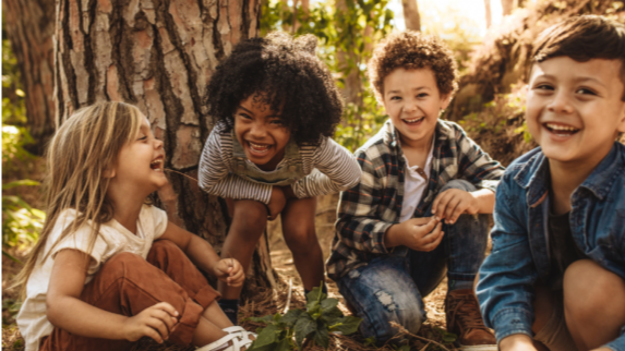 Children of different race playing with one another in a forrest.