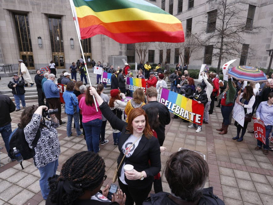 In this Feb. 9, 2015 file photo, Amanda Keller holds a flag as she joins other gay marriage supporters in Linn Park, at the Jefferson County courthouse in Birmingham, Ala.