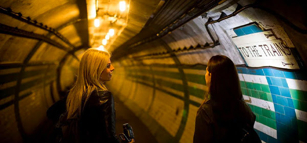 Two woman looking down underground tunnel