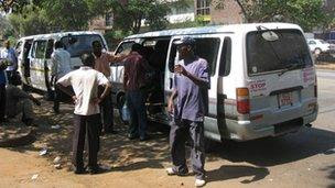 People standing by mini bus taxis in Harare, Zimbabwe