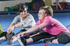 Image of a teen with a disability exercising with an adult fitness instructor. 