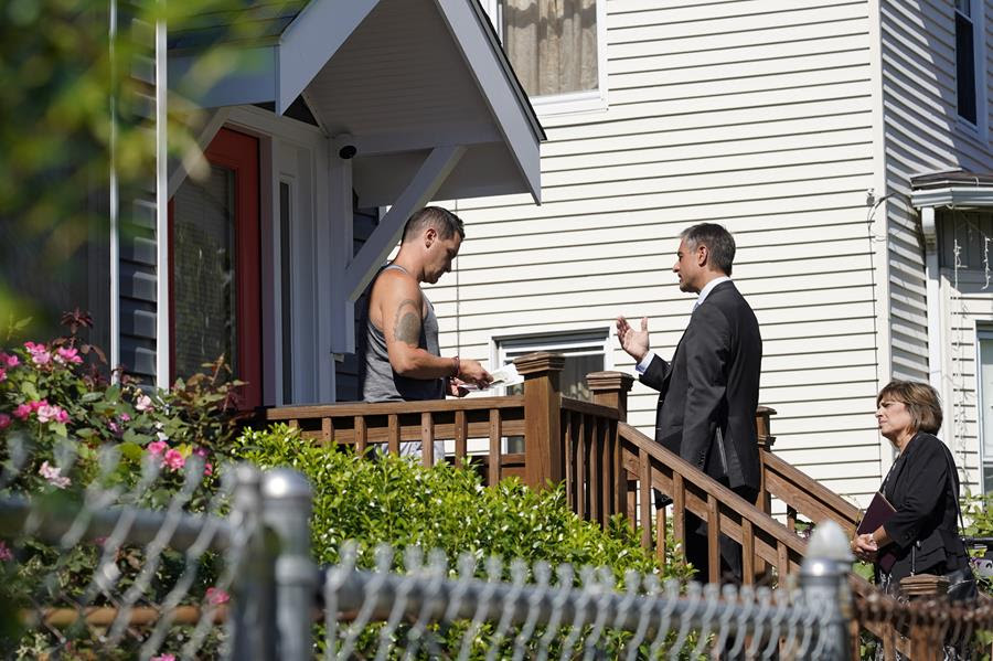 Dan Sideris, center, talks with a resident on a front porch accompanied by his wife, Carrie Sideris, as the couple returns to door-to-door visits as Jehovah's Witnesses, Thursday, Sept. 1, 2022, in Boston.