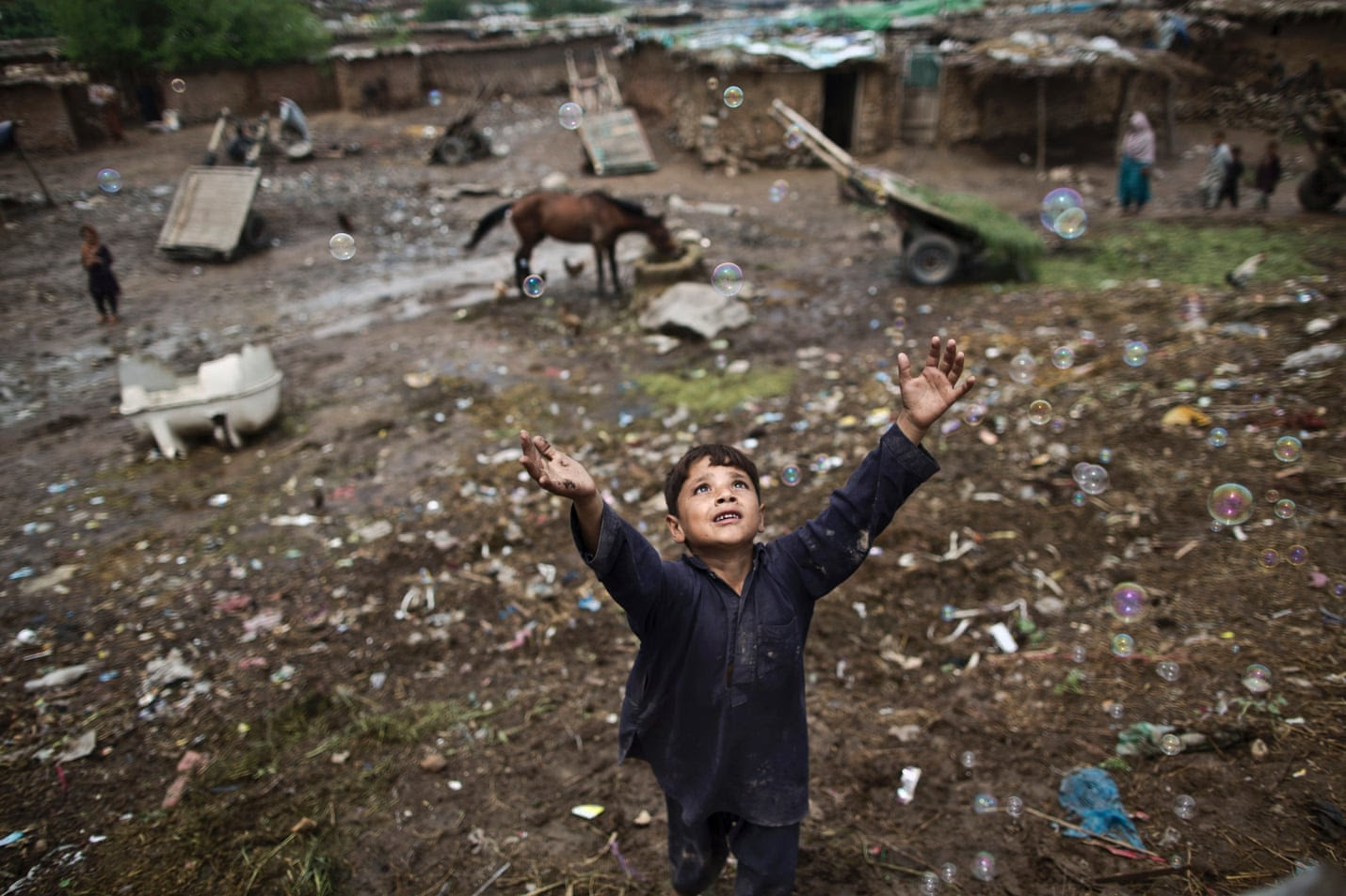 An Afghan refugee boy chases bubbles while playing on the outskirts of Islamabad, Pakistan