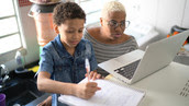 Mother helping her son with a laptop during an online class at home.