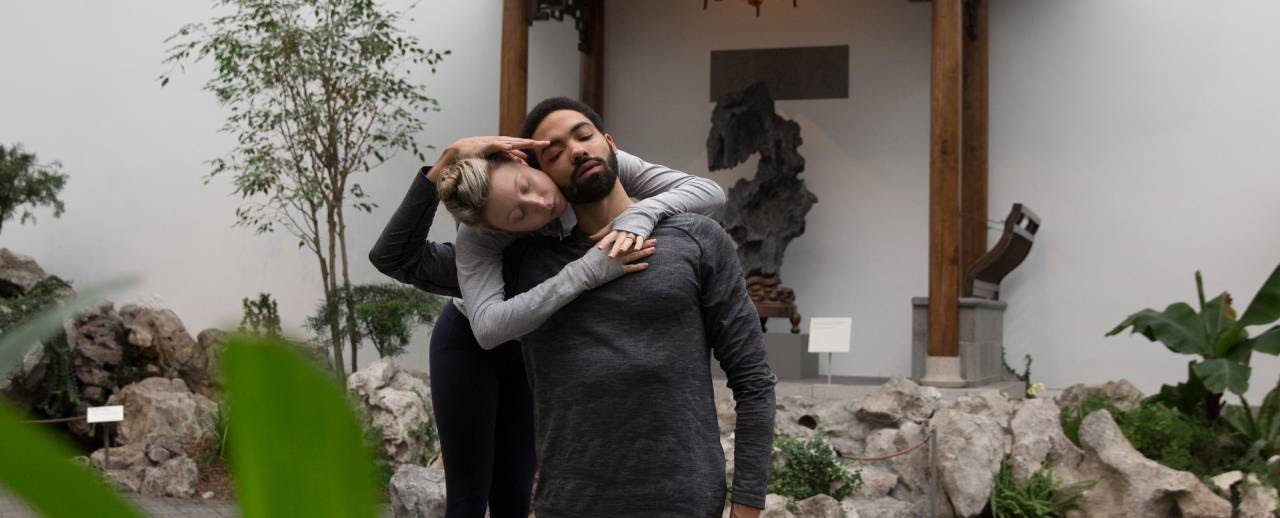 Imagem de jovens dançarinos, uma mulher e um homem, posando no The Astor Chinese Garden Court