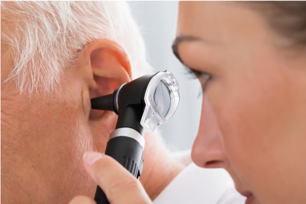 Doctor examines elder's ear with an otoscope.