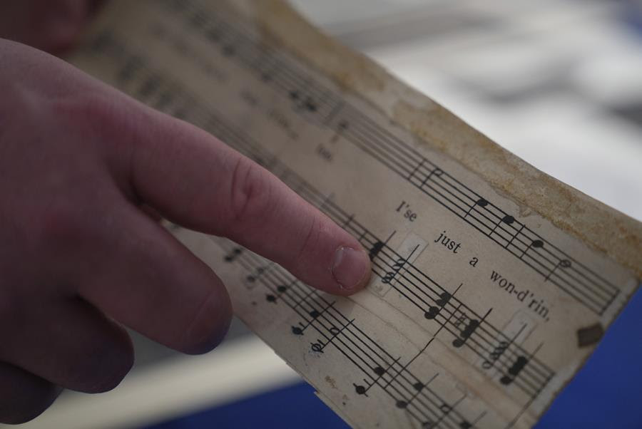 Someone points to the notes on a piece of sheet music.