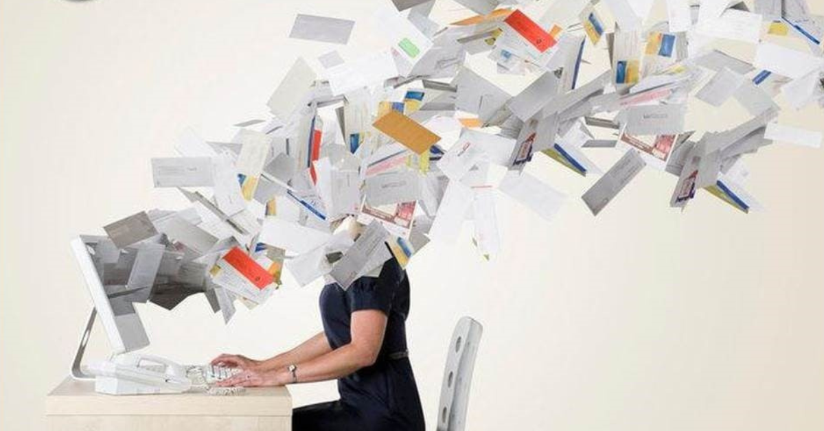 woman on computer overwhelmed with papers flying out of the screen