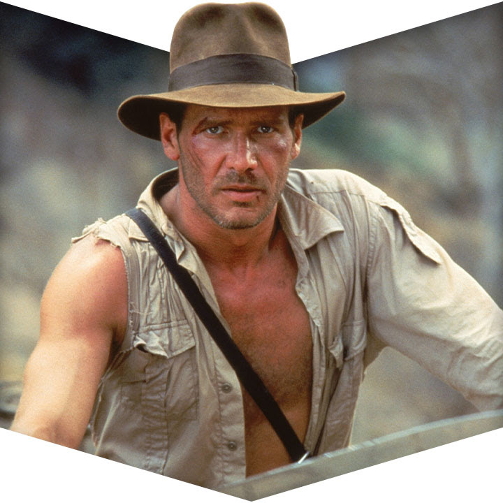 Harrison Ford as Indiana Jones looks forward in a torn shirt and his signature hat