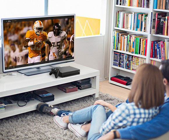 Man and woman sitting on couch watching an American football game.