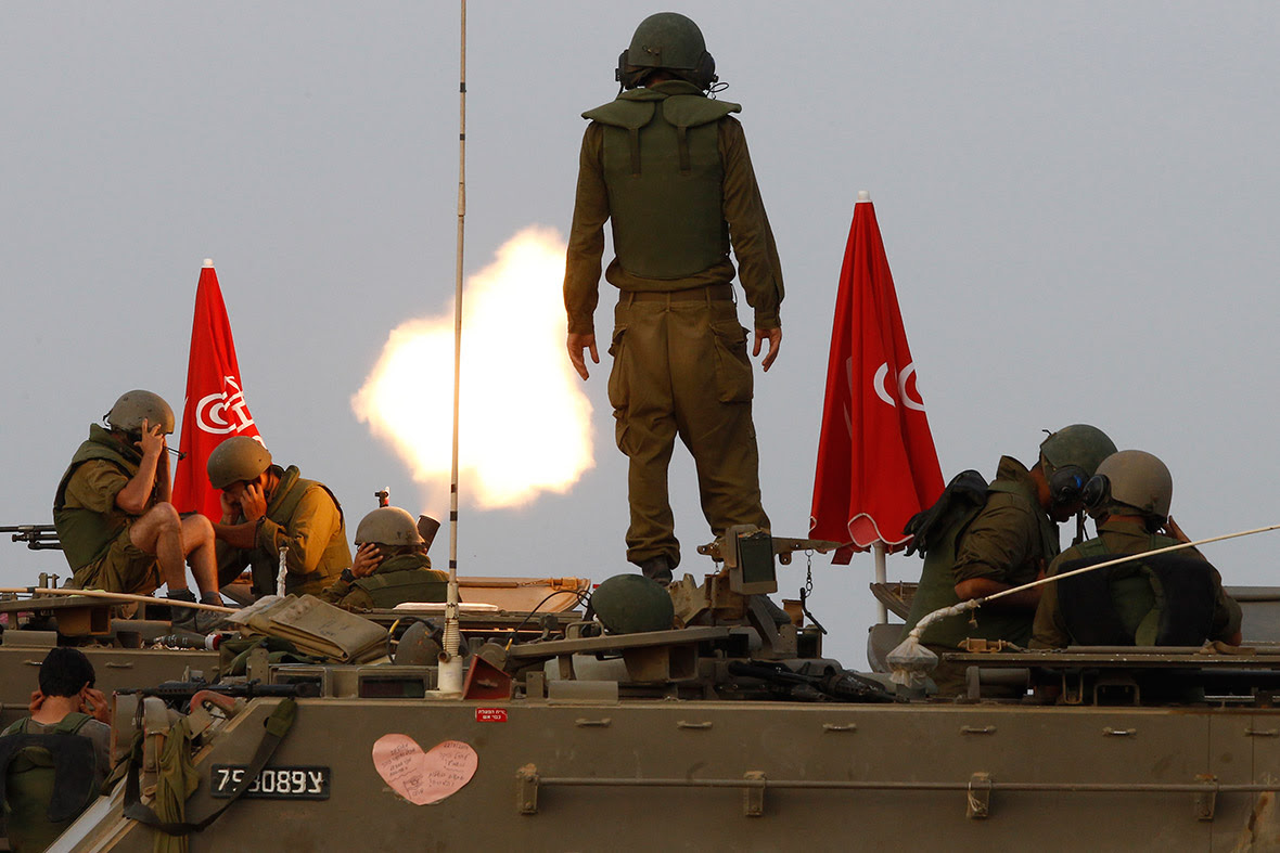 Israeli soldiers stand on an armoured personnel carrier (APC) outside the central Gaza Strip as they fire mortar shell towards Gaza before a ceasefire was due, early on August 1, 2014