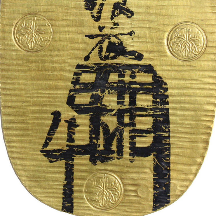 Portion of a gold coin stamped with symbols and with black writing on