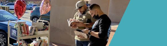 Two men reading library books outside