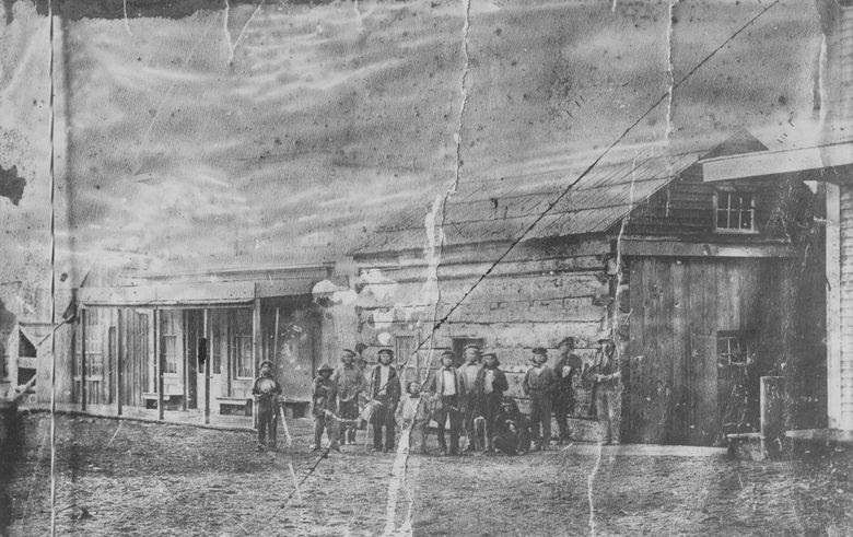 A group of Indigenous workers stands in front of the cookhouse at Henry Yesler’s sawmill in 1866. (University of Washington Libraries, Special Collections, UW 5870)