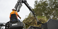 A man in safety gear uses a loading machine to place vegetation and debris in an enormous truck. Source: Robert Kaufmann, FEMA