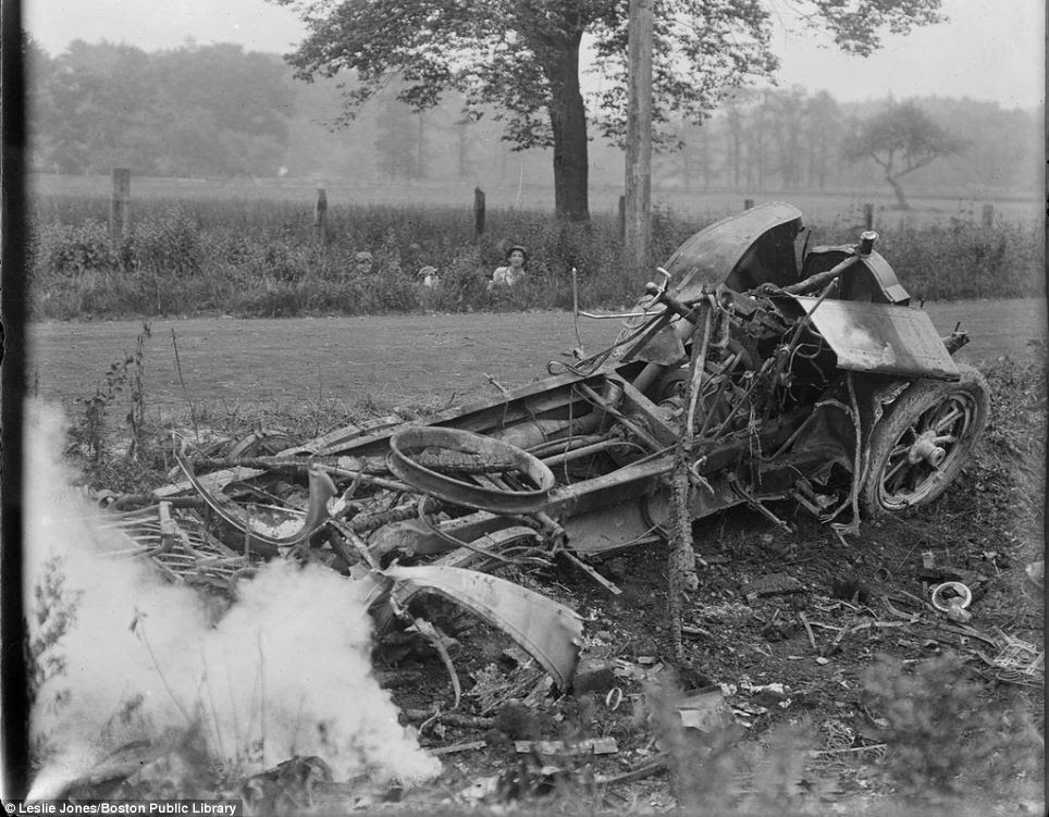 Children peer out of the undergrowth as photographer Leslie Jones captures a nasty wreck smoulding by the side of the road in Hingham