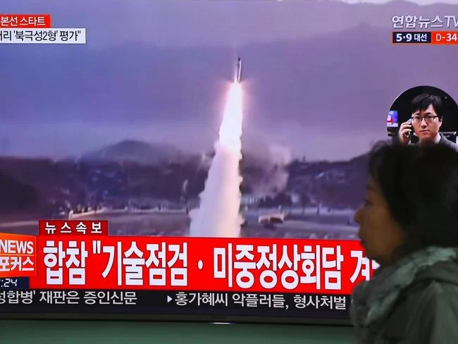 A woman walks past a television screen showing file footage of a North Korean missile launch, at a railway station in Seoul on April 5. Picture: AFP