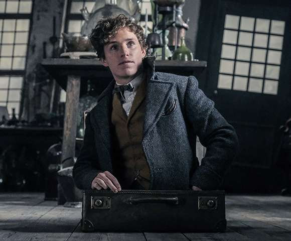 Eddie Redmayne as Newt Scamander wearing a three-piece suit with heavy overcoat.