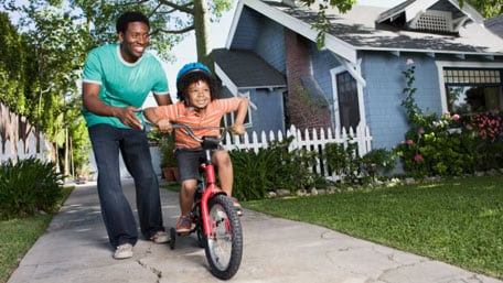 Un padre enseña a su hijo a andar en bicicleta. 